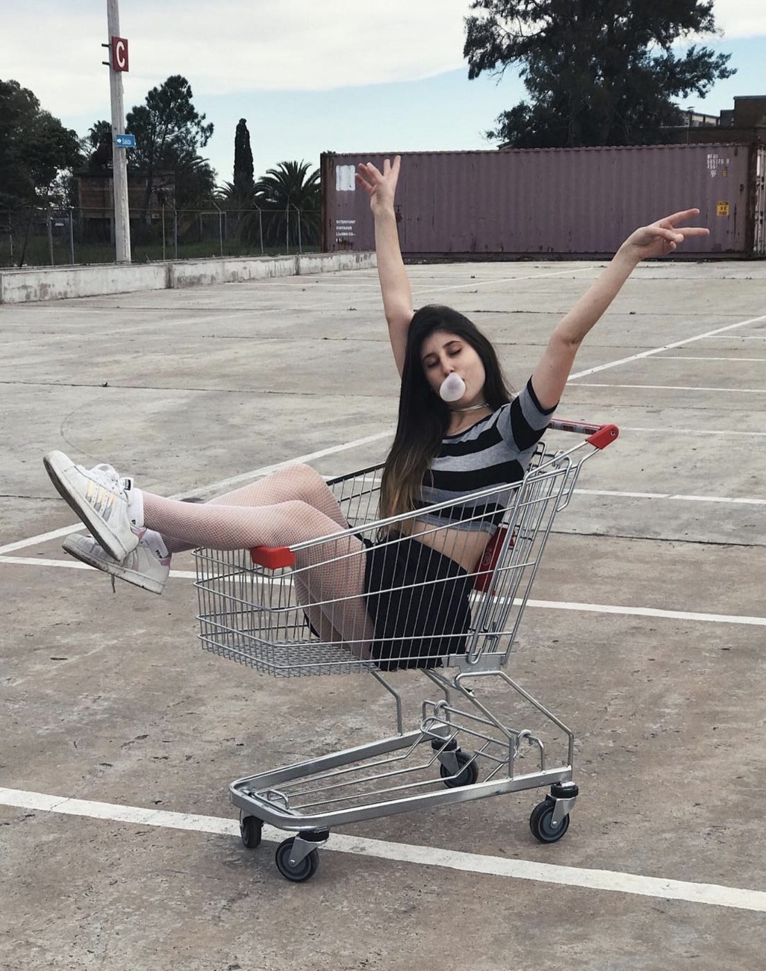 Victoria en 2015, sentada en un carrito de supermercado haciendo un globo de chicle
