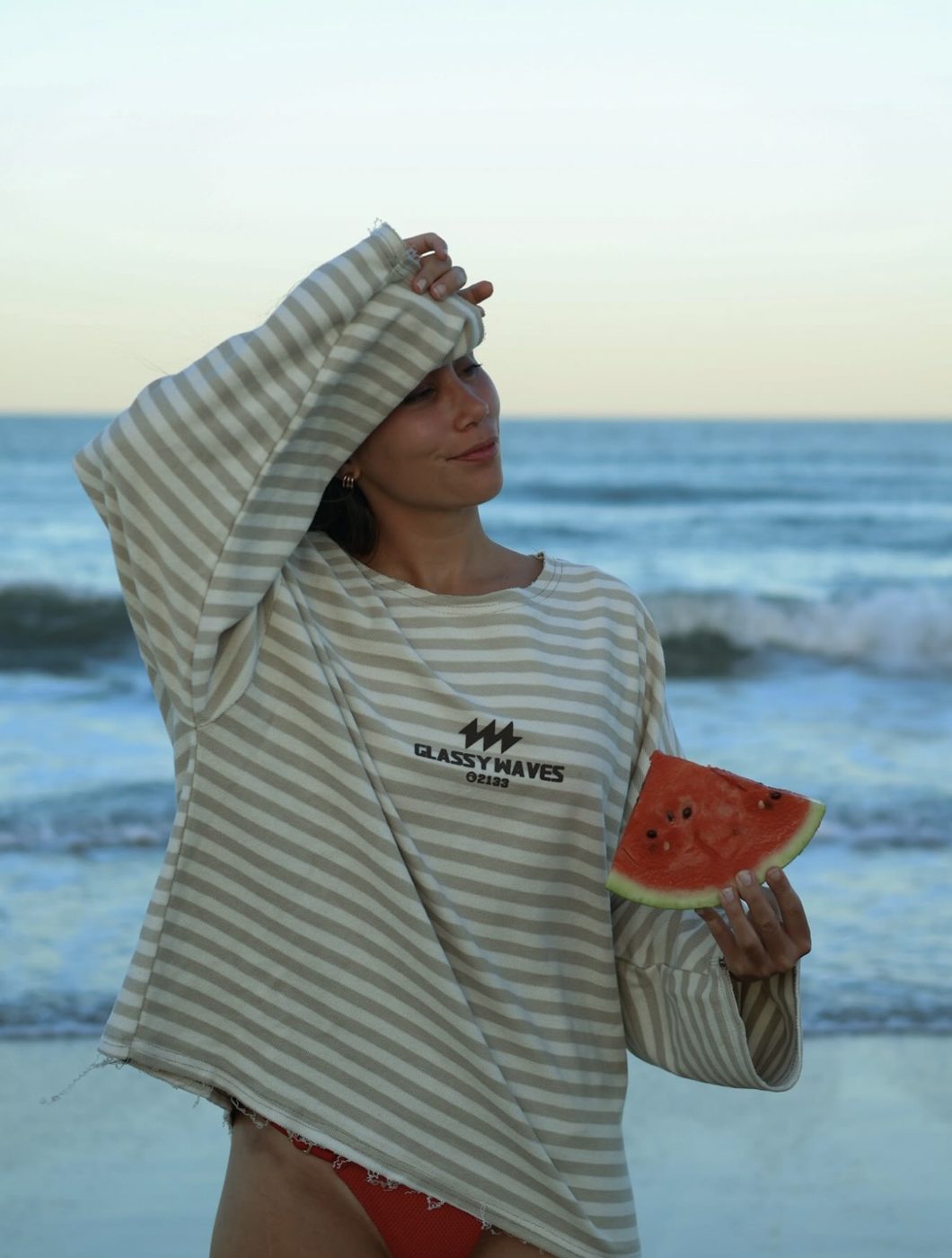 Victoria en la playa con buzo rayado de GlassyWaves y una tajada de sandía